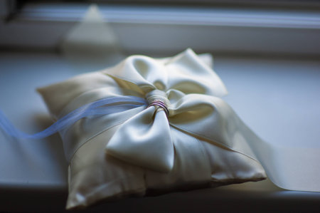 wedding rings lying on a beige satin cushionの写真素材