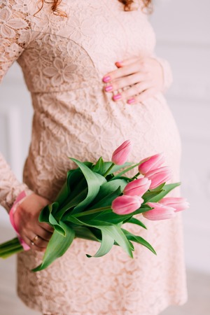 Belly of pregnant girl and tulips in handsの写真素材