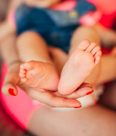 Little legs of the child, lies on the hands of the parents. Newborn baby.