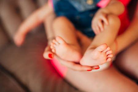 Little legs of the child, lies on the hands of the parents. Newborn baby.