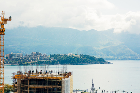 Construction of a multistory building in Budva, Montenegro. Builders are building a house. Crane working at a construction site. Sticks reinforcement of concrete.の写真素材