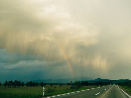 Rainbow over the highway. View from the car interior.の写真素材