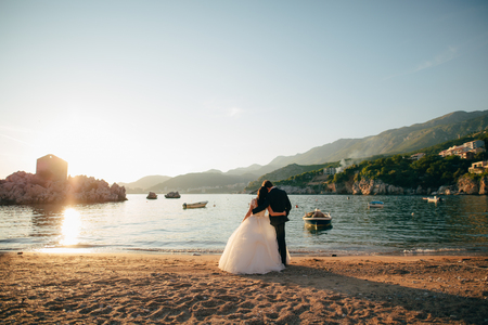 Bride and groom on the beach of the Queen Milocer , stand back and look at the island of Sveti Stefan in Montenegro.の写真素材