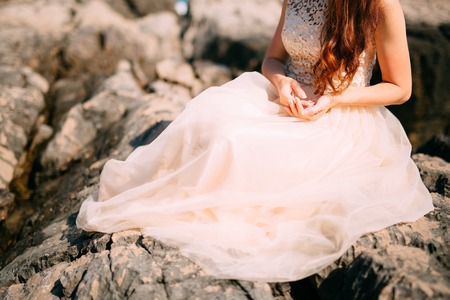 Girl playing with hair. The red bride plays with curls on the rocks by the sea. Wedding in Montenegro.の写真素材