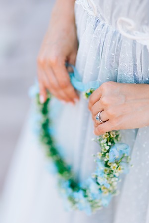 Wreath on a head of blue and white flowers in the brides hand in a blue dress.の写真素材