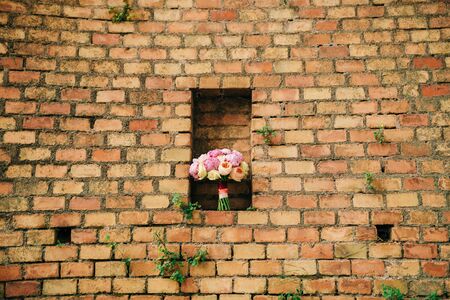 Bouquet of peonies on the background of the stone wall of red brickの写真素材