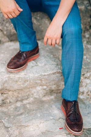Brown shoes on male legs. The groom in a blue pants.