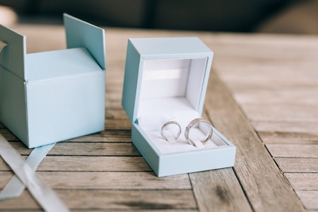 Wedding rings on a light wooden texture in a blue box. Wedding jewelry.の写真素材