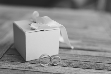 Wedding rings on a light wooden texture in a blue box. Wedding jewelry. Black and white photography.の写真素材
