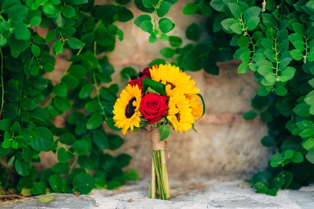 Wedding bridal bouquet of sunflowers in on a stone bench and hanging on the background of green leaves. Wedding in Montenegro, Perast.の写真素材