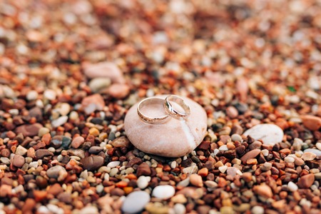 Wedding rings on the beach pebbles. Wedding jewelry. Sea Wedding.の写真素材