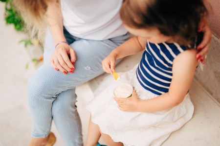 Mom and daughter are eating ice cream on a bench in the park.の写真素材