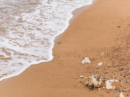 Sandy beach and waves, close-up. Texture of sand and water. Picture for the postcard. Vacation at sea. Advertising of the sea.の写真素材