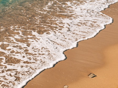 Sandy beach and waves, close-up. Texture of sand and water. Picture for the postcard. Vacation at sea. Advertising of the sea.の写真素材