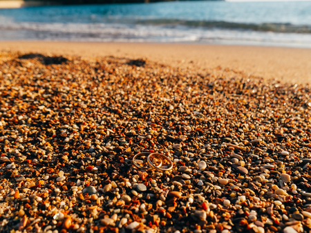 Wedding rings on the beach pebbles. Wedding jewelry. Sea Wedding.の写真素材