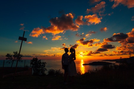 Silhouette of a newlywed couple at the sea at sunset. Wedding in Montenegro. Silhouettes of the couple, the bride and groom.の写真素材