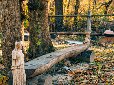 Statues without hands beside a wooden bench in the forestの写真素材