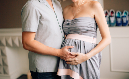 Husband hugging pregnant wife. Hands of a man on a womans belly. Hands touching belly.の写真素材