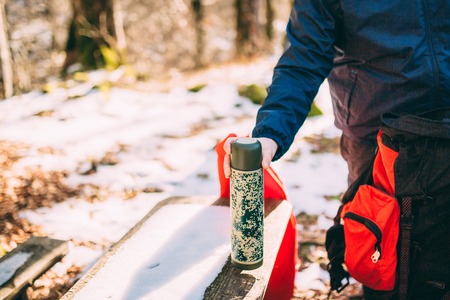 Tourists on a halt drinking tea from a bottle in snowy winter forest.の写真素材