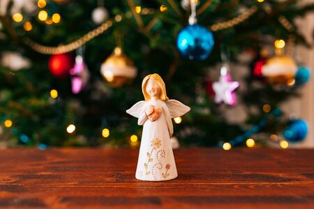 Christmas angel on a wooden table on a background of treesの写真素材