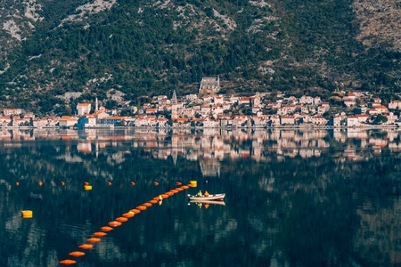Fishermen in a boat are fishing. Kotor Bay, a view of the city of Perast and the island of Gospa od Skrpela, Montenegro.の写真素材