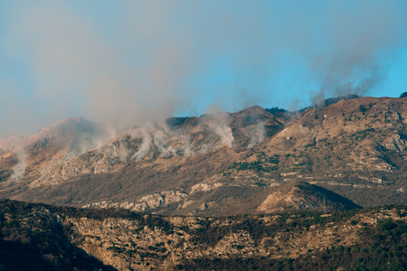 Fire in the mountains in the afternoon. Smoke over the mountains. Budva, Montenegro. Forest fires.の写真素材