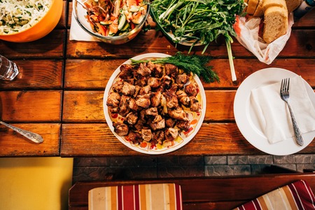 Shish kebab on skewers in a plate on a wooden table.の写真素材