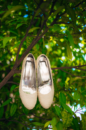 brides shoes lie on the green grass in the forest next to a wedding bouquet of flowers and greeneryの写真素材
