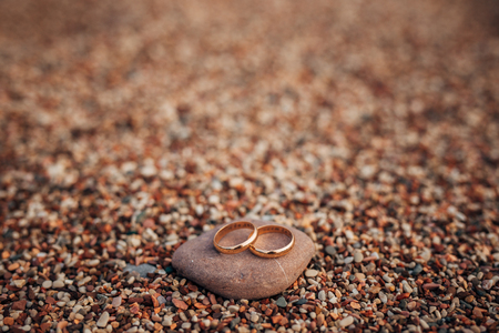 Wedding rings of newlyweds on beach pebbles. Engagement gold rings. Wedding in Montenegro.の写真素材