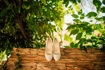 brides shoes lie on the green grass in the forest next to a wedding bouquet of flowers and greeneryの写真素材