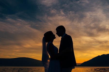 Silhouette of a newlywed couple on the background of the setting sun on the sea in Montenegro.の写真素材