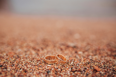 Wedding rings of newlyweds on beach pebbles. Engagement gold rings. Wedding in Montenegro.の写真素材