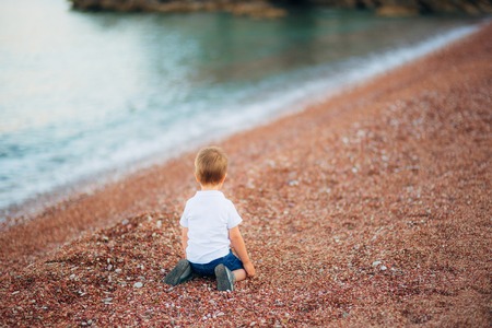 A frustrated child cries on a pebble beach in Montenegro.の写真素材