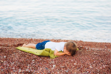 A frustrated child cries on a pebble beach in Montenegro.の写真素材