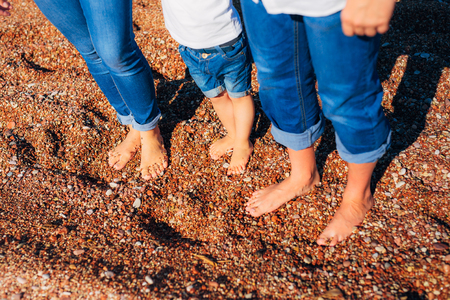 Childrens legs and feet of parents. The family walks along the beach in Montenegro.の写真素材