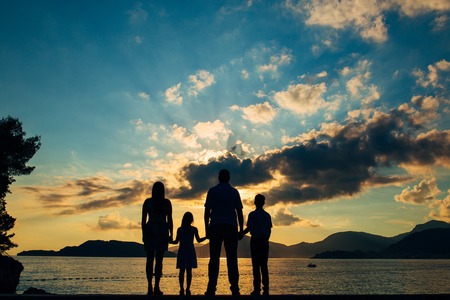 Silhouette of a family with children against the backdrop of the setting sun and sea in Montenegro.の写真素材