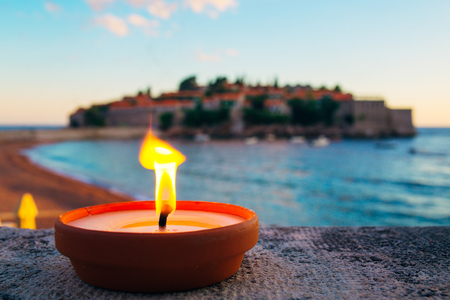 Burning candle on the beach against the background of Sveti Stefan in Montenegroの写真素材