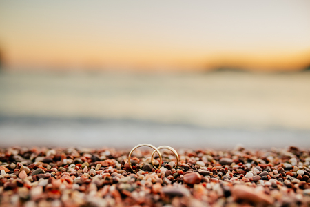 Wedding rings of newlyweds on beach pebbles. Engagement gold rings. Wedding in Montenegro.の写真素材