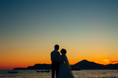 Silhouettes of couples near Sveti Stefan island in Montenegroの写真素材