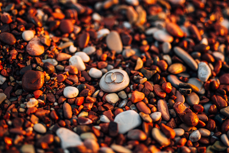Wedding rings of newlyweds on beach pebbles. Engagement gold rings. Wedding in Montenegro.の写真素材