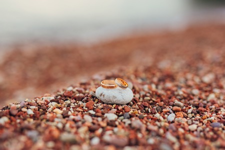 Wedding rings of newlyweds on beach pebbles. Engagement gold rings. Wedding in Montenegro.