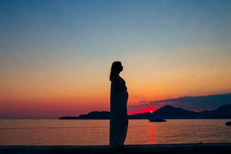 Silhouette of a pregnant woman at sunset by the sea Montenegroの写真素材
