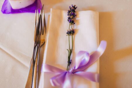 Wedding table setting at a banquet. A plate and instruments tied with a purple ribbon.の写真素材