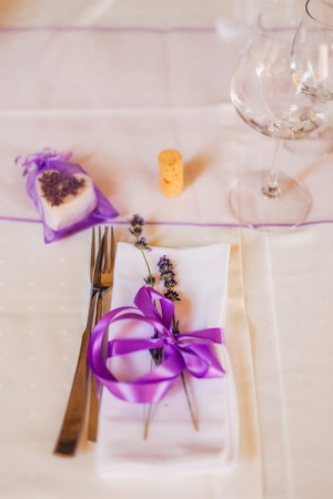 Wedding table setting at a banquet. A plate and instruments tied with a purple ribbon.の写真素材