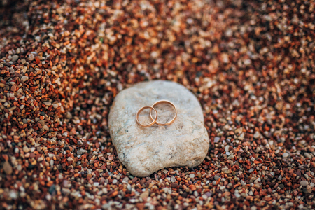 Wedding rings of newlyweds on beach pebbles. Engagement gold rings. Wedding in Montenegro.の写真素材