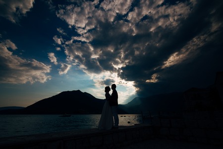 Silhouette of a newly-married couple on the background of the setting sun in Perast in Montenegro.の写真素材