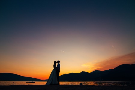 Silhouette of a newlywed couple on the background of the setting sun on the sea in Montenegro.の写真素材