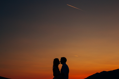 Silhouette of a newlywed couple on the background of the setting sun on the sea in Montenegro.の写真素材