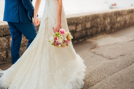 Happy beautiful bride outdoors. Wedding dress fluttering in the wind. Building in the background.の写真素材