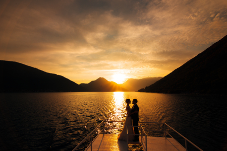 Silhouette of a newlywed couple on the background of the setting sun on the sea in Montenegro.の写真素材